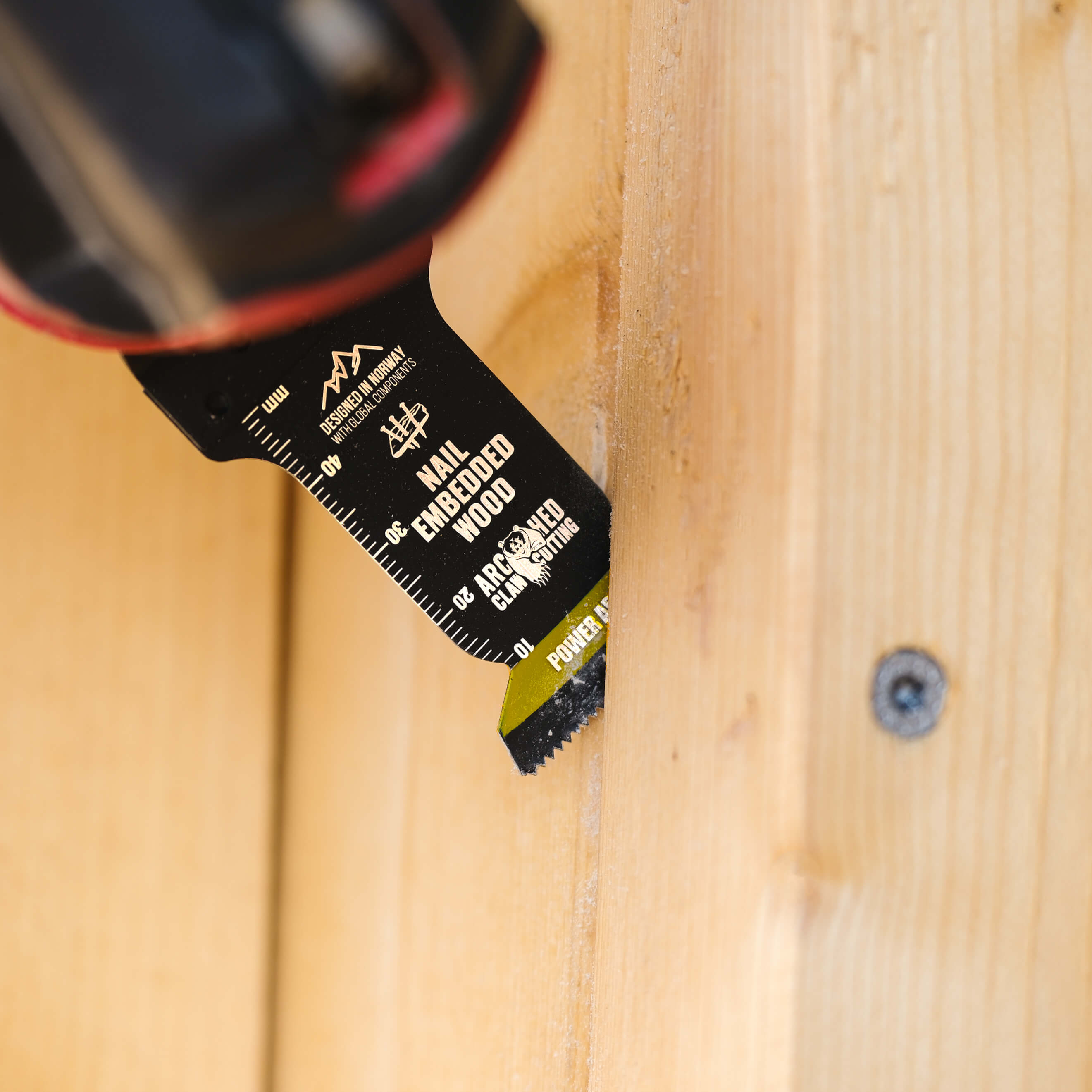 a multi-tool saw blade cutting wood with a screw in it
